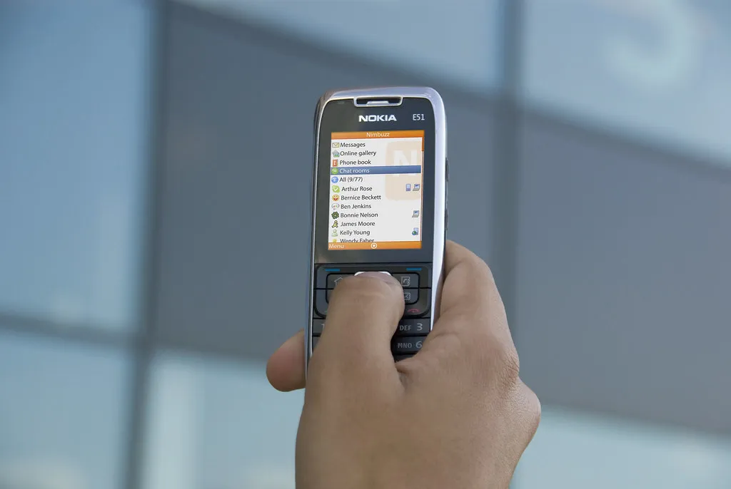 Hand holding a phone showing a list of recent card transactions in a banking app