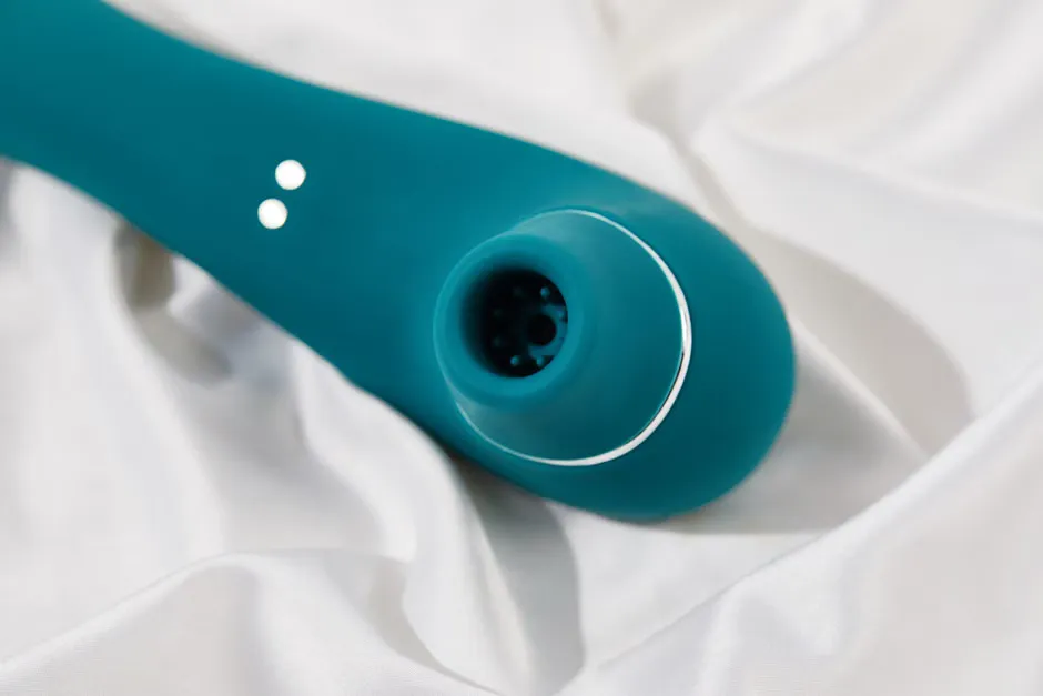Close-up of a smooth silicone toy, a clear glass toy and a polished steel toy on a pale stone bench